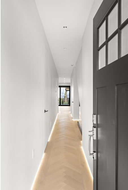 Herringbone hallway with lit skirting detail and glazed front door
