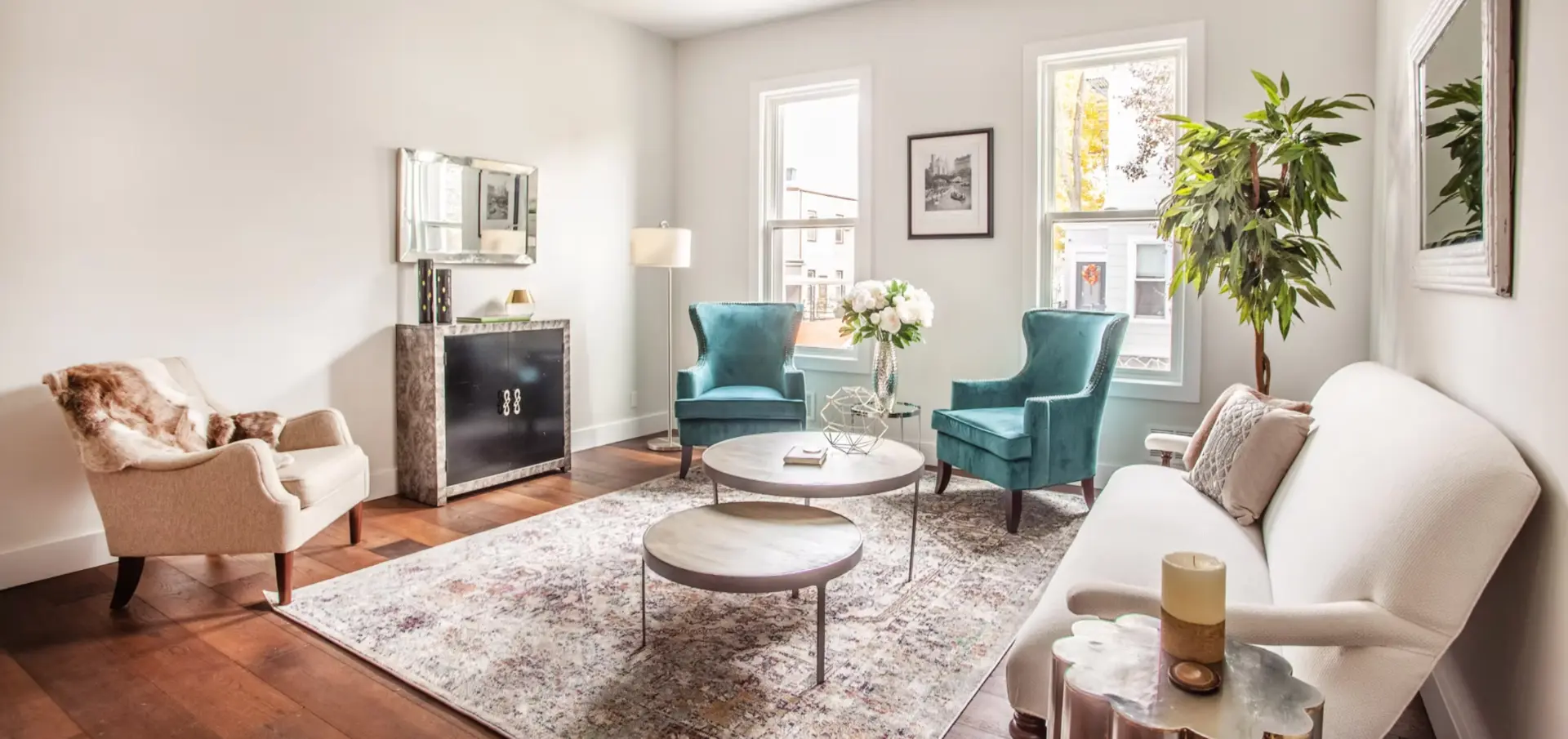Reception room with teal armchairs, restored hardwood flooring and bay windows