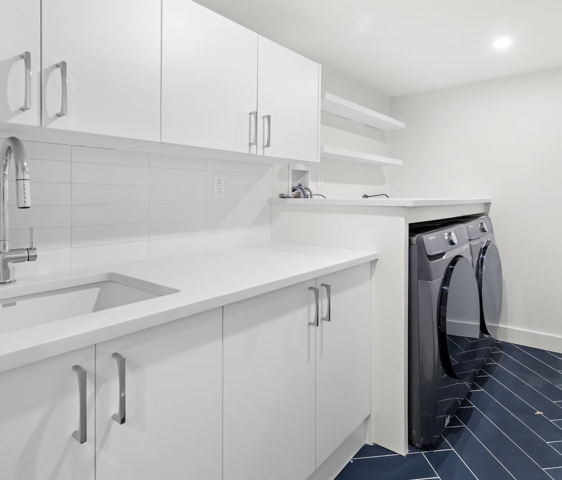 Utility room with white joinery and herringbone tiled floor