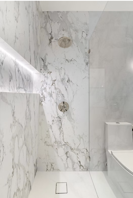 Book matched marble walk in shower with lit recess