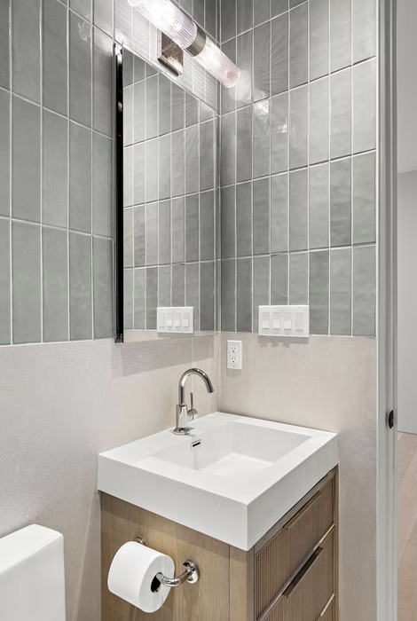 Cloakroom with green tile, timber vanity and black framed mirror