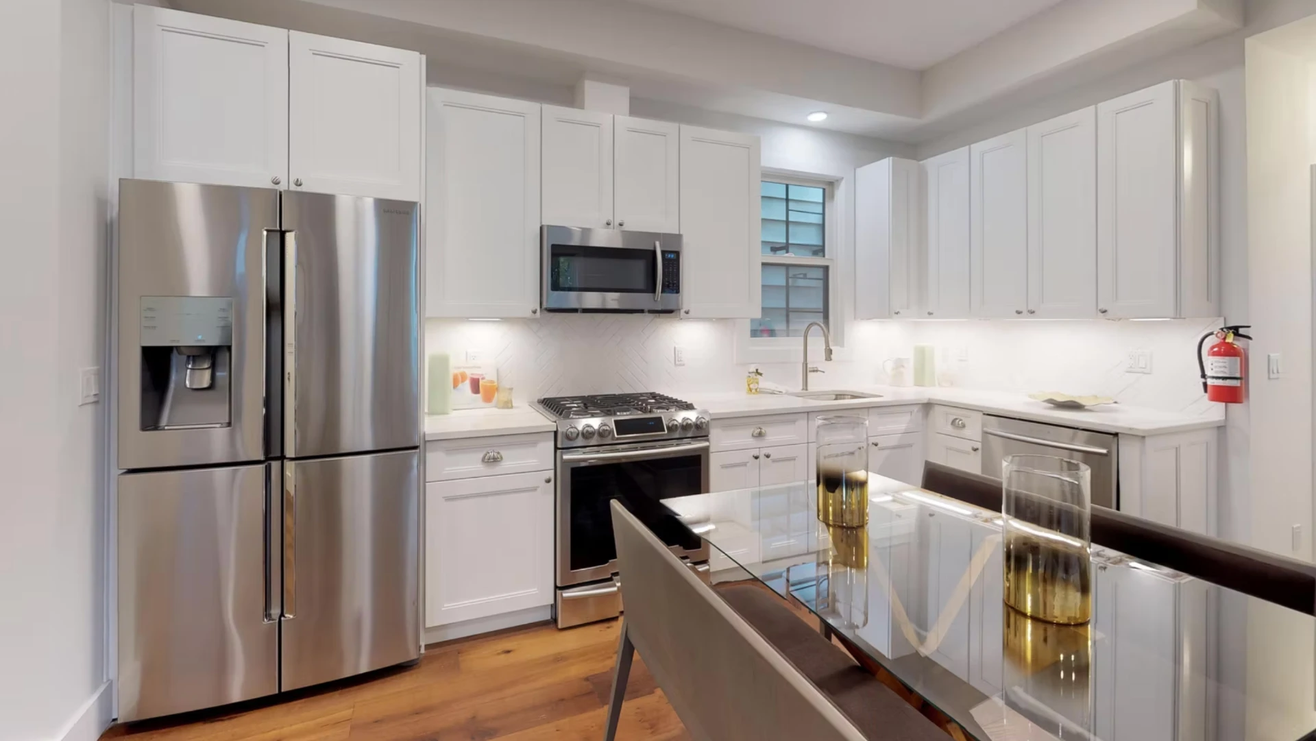 Open plan kitchen with stainless appliances and glass dining table