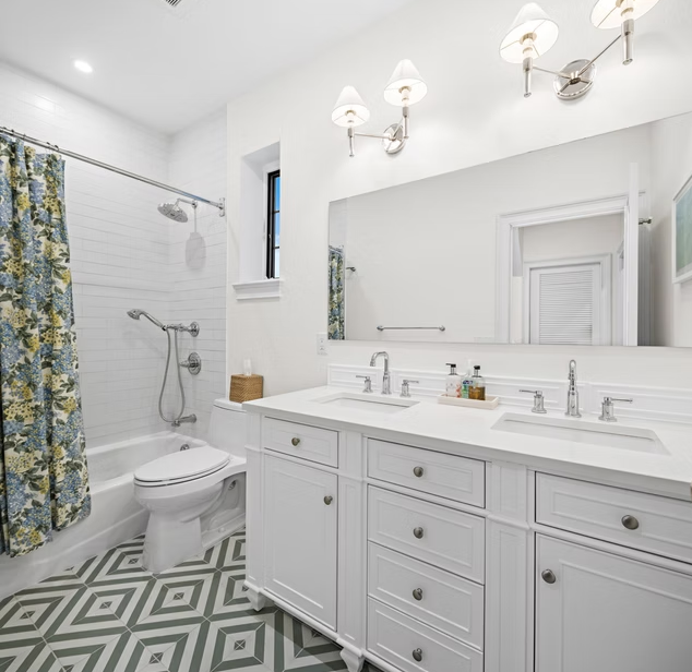 Family bathroom with white vanity, twin basins and patterned tiled floor