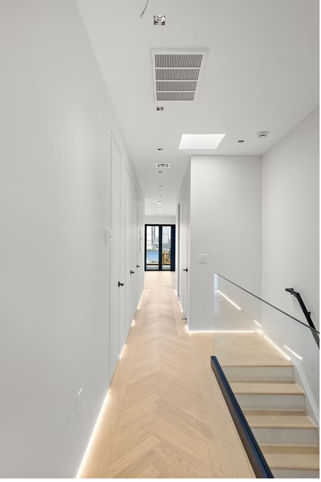 Hallway with herringbone flooring and glass balustraded stair