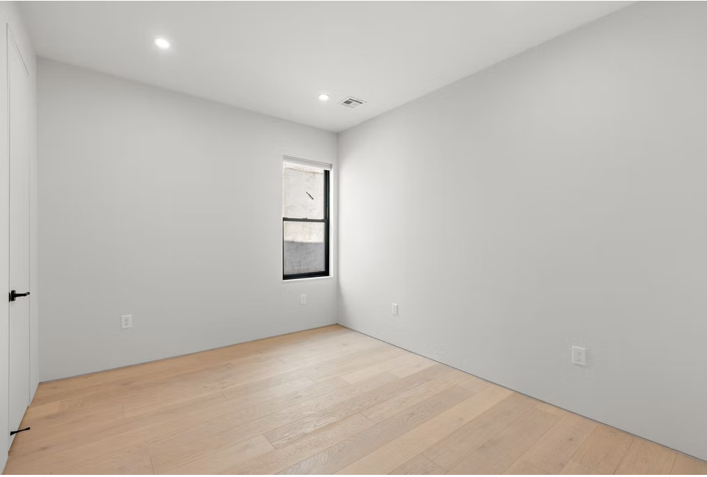 Bedroom with black framed window and oak flooring