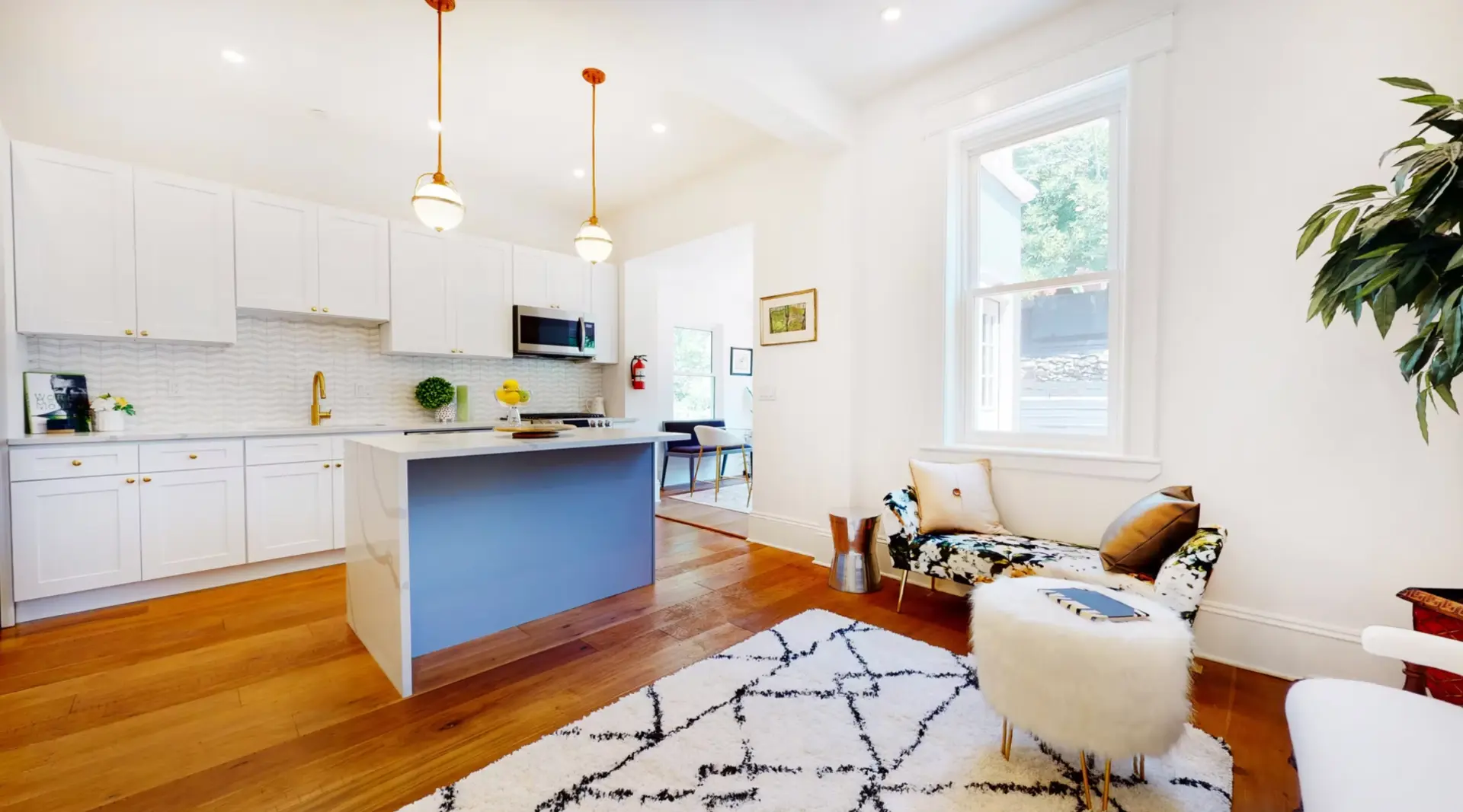 Open plan kitchen and living room with blue island and hardwood flooring