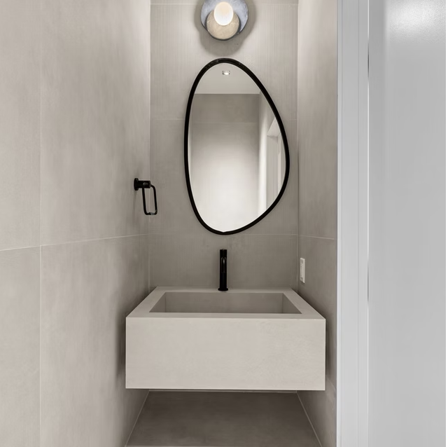 Cloakroom with sculptural mirror and stone basin