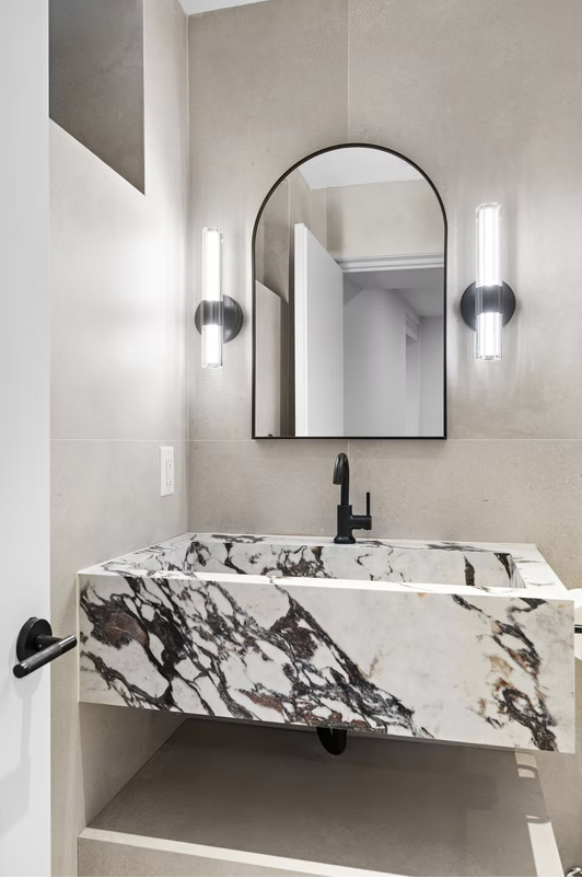 Cloakroom with sculptural marble basin and arched mirror