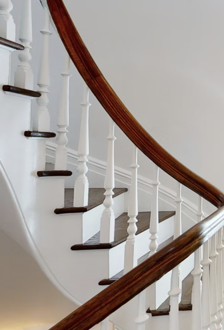 Restored curved staircase with white balustrade and polished timber handrail