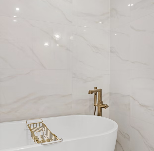 Freestanding bath against full height marble tiling with brass filler