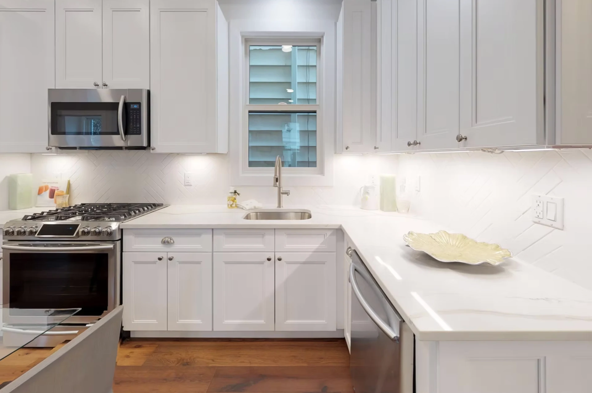 White shaker kitchen with stone worktops and herringbone tiled splashback