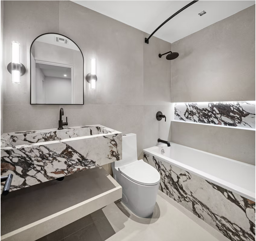 Micro cement bathroom with marble bath surround and arched mirror