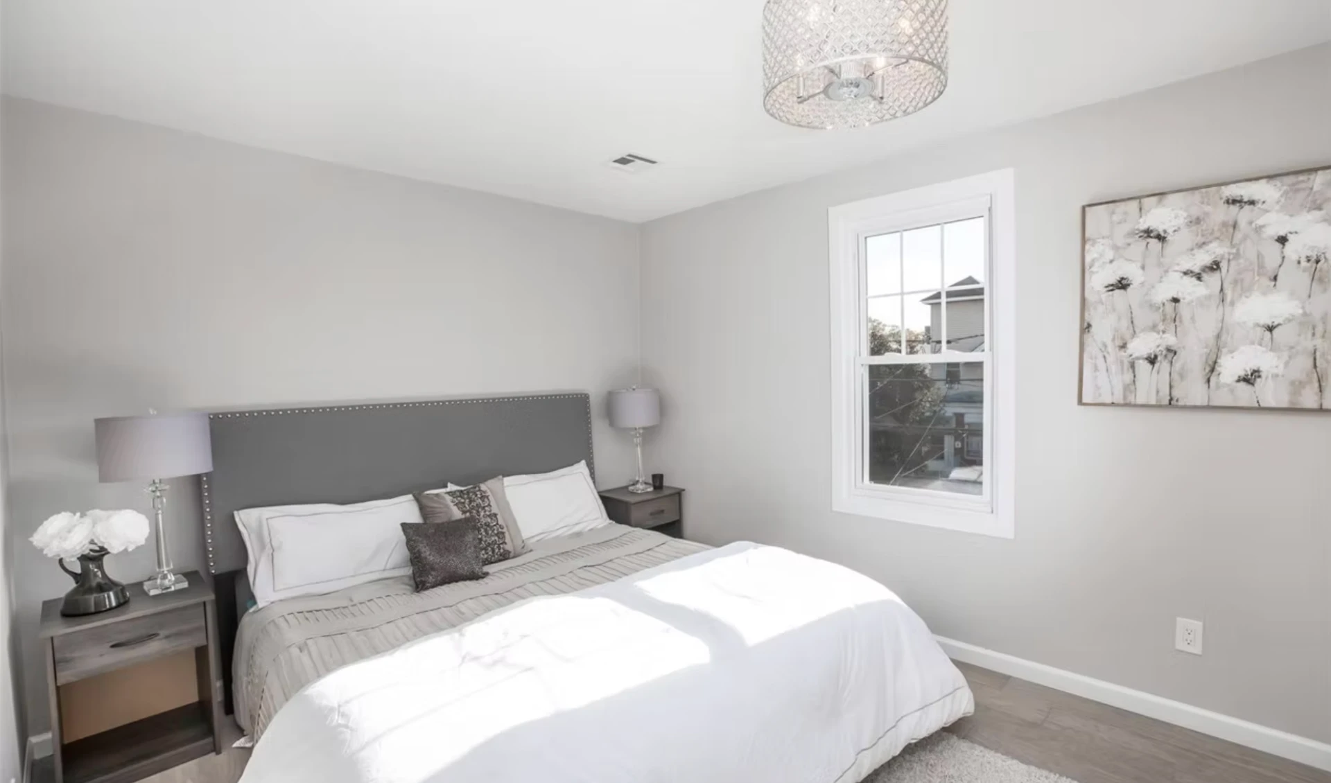 Principal bedroom with upholstered headboard and pale timber flooring