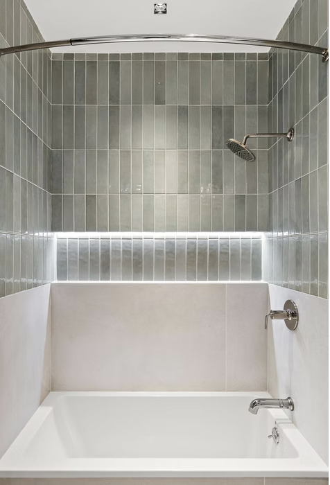 Bath with green tiled surround and lit recess