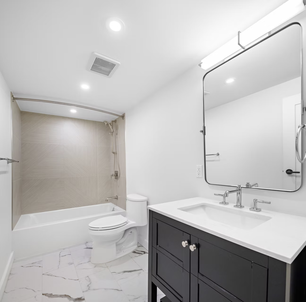 Family bathroom with dark vanity and marble tiled floor
