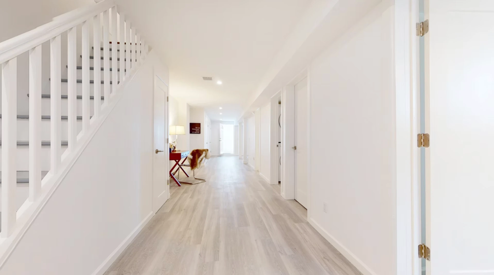 Hallway with restored stair, pale timber flooring and concealed joinery