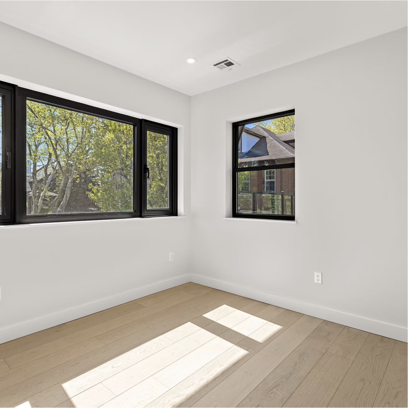 Corner bedroom with black framed windows and garden views