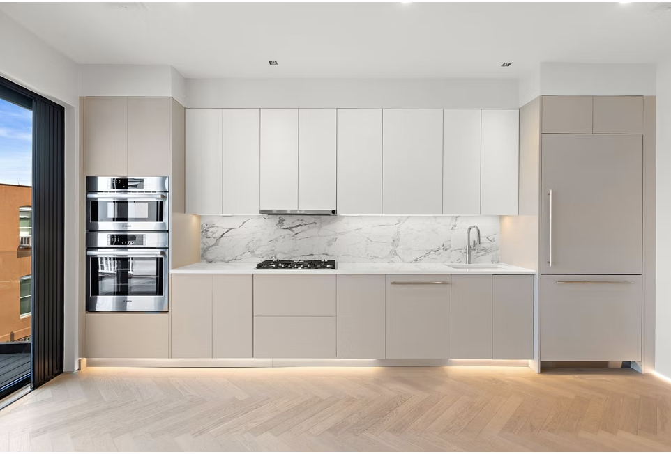 Handleless kitchen with marble splashback and integrated appliances