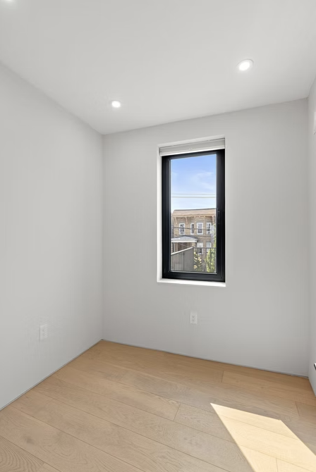 Bright bedroom with tall window and rooftop views