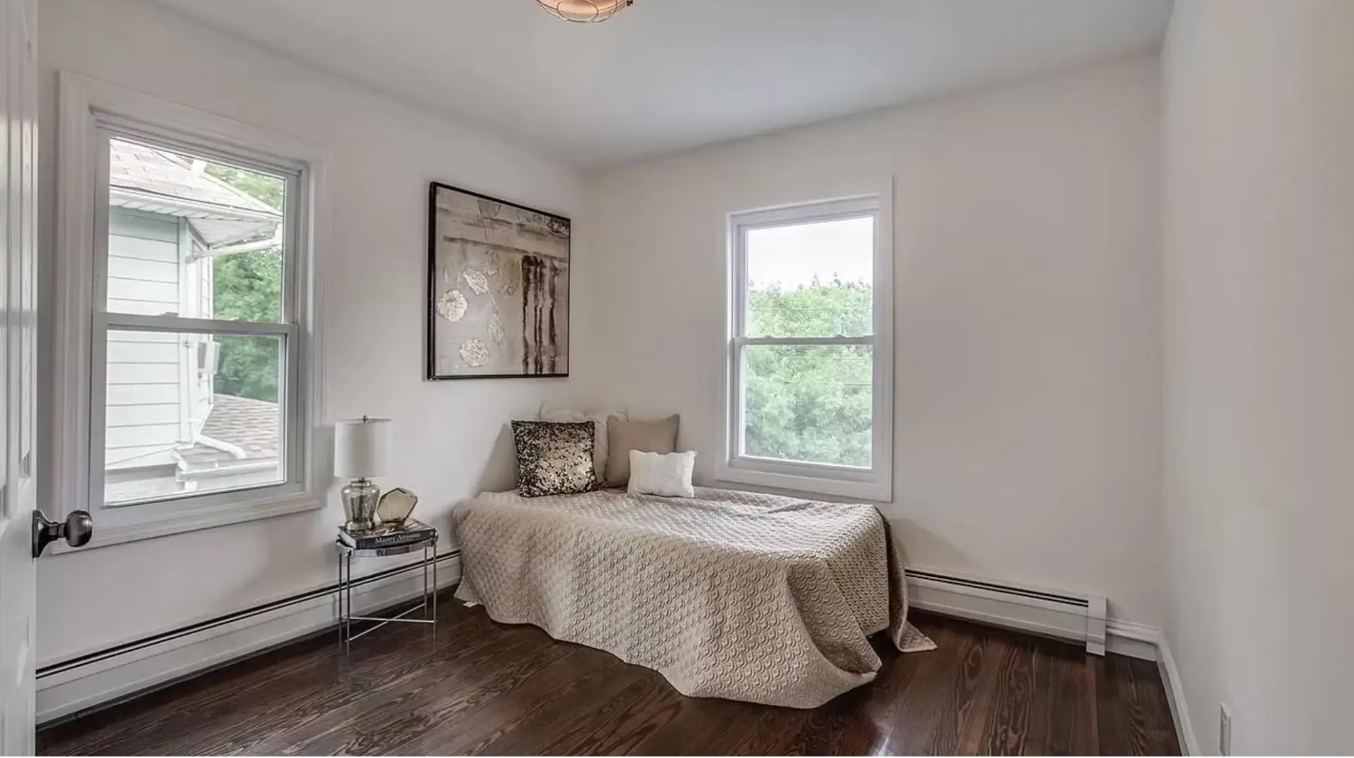 Guest bedroom with twin windows and hardwood flooring