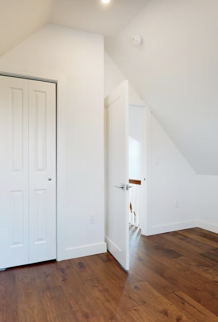 Loft landing with fitted wardrobe doors and pitched white ceiling