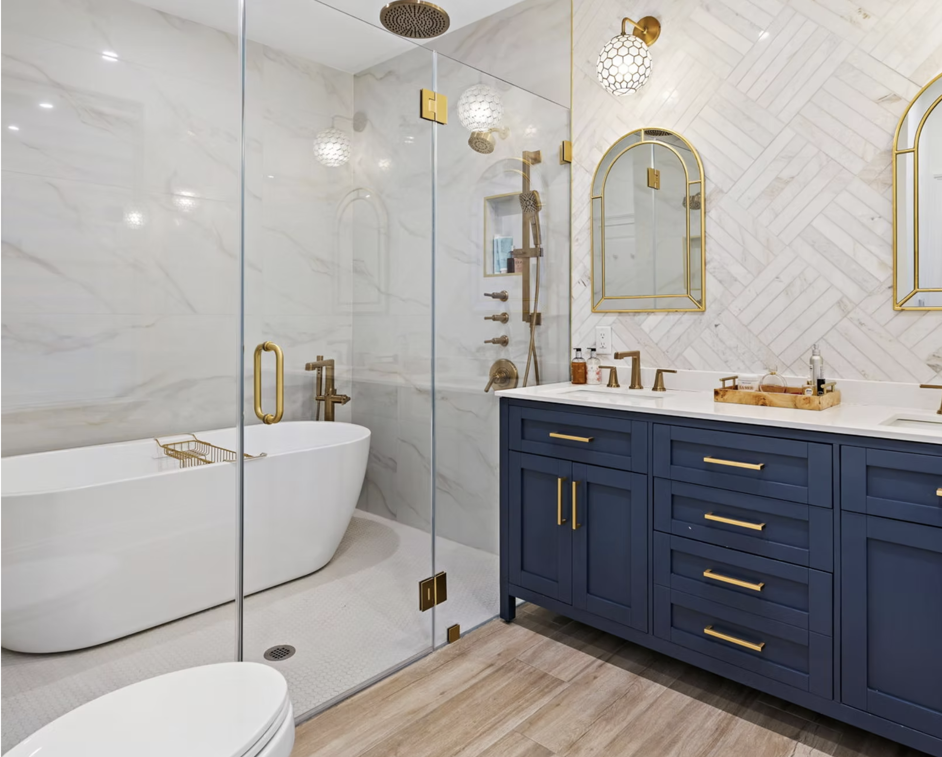 Principal bathroom with navy double vanity, brass fittings and herringbone marble