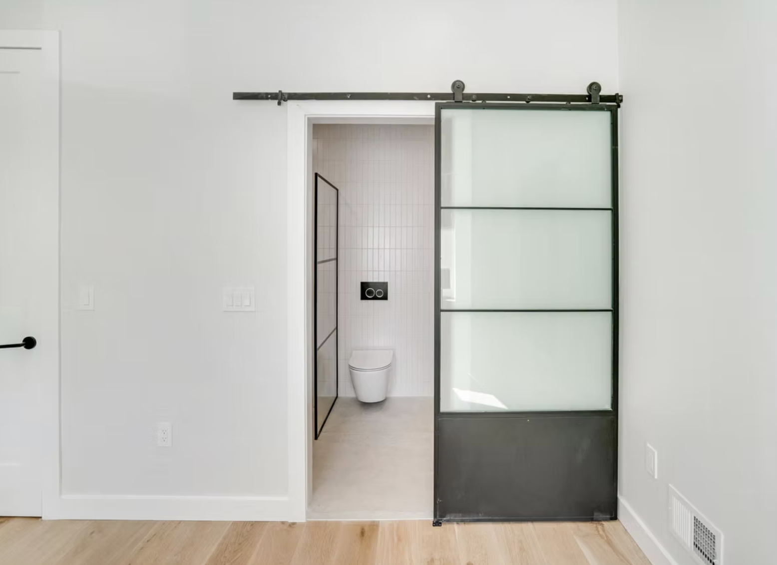 Steel and glass sliding door to a tiled cloakroom