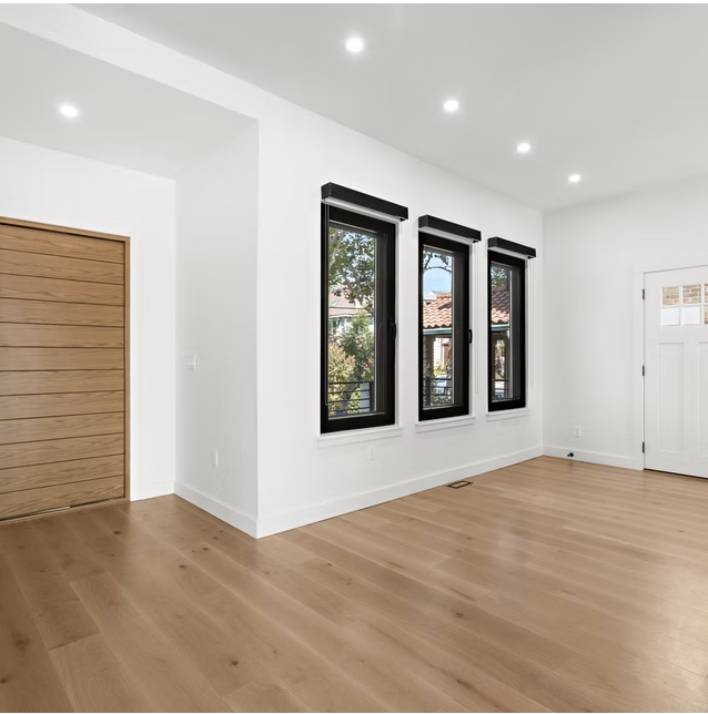 Reception room with three black framed windows and oak door