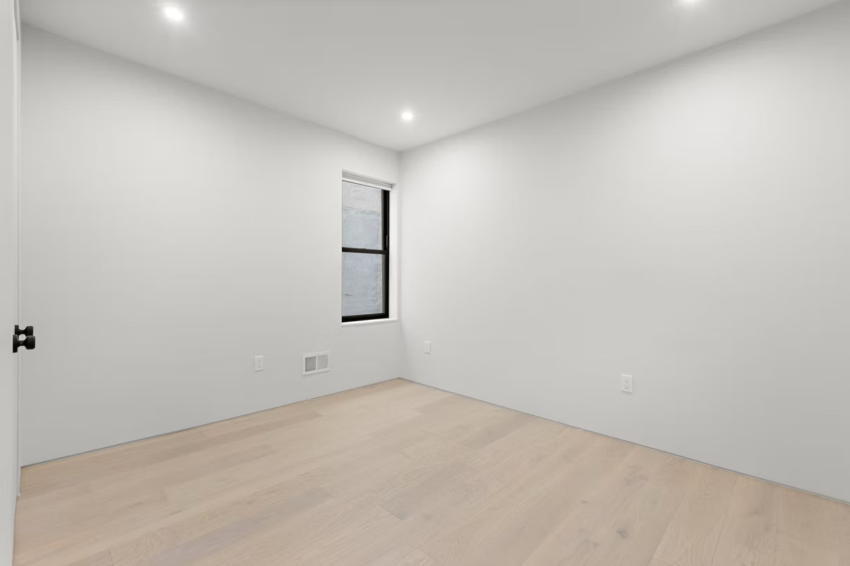 Bedroom with oak flooring, black framed window and recessed lighting