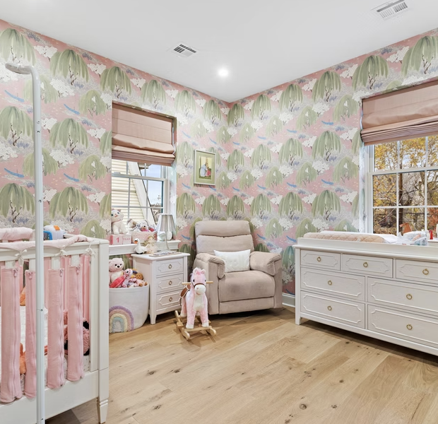 Nursery with botanical wallpaper, oak flooring and fitted dresser