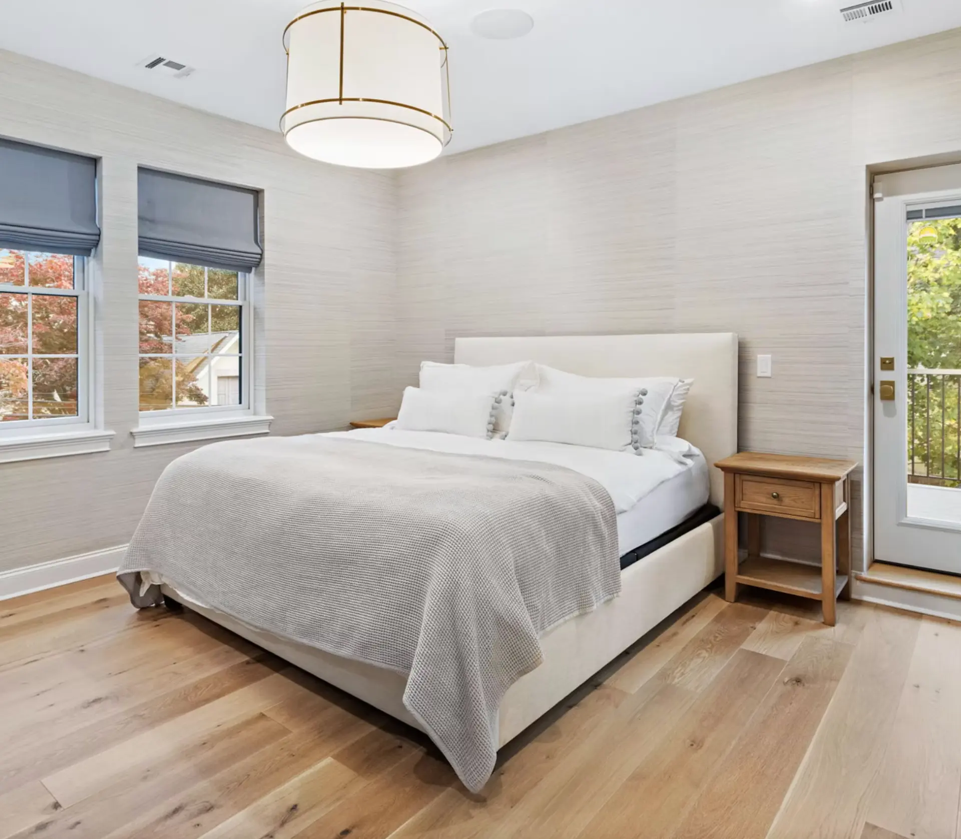 Loft bedroom with pitched white ceiling, fitted desk and oak flooring