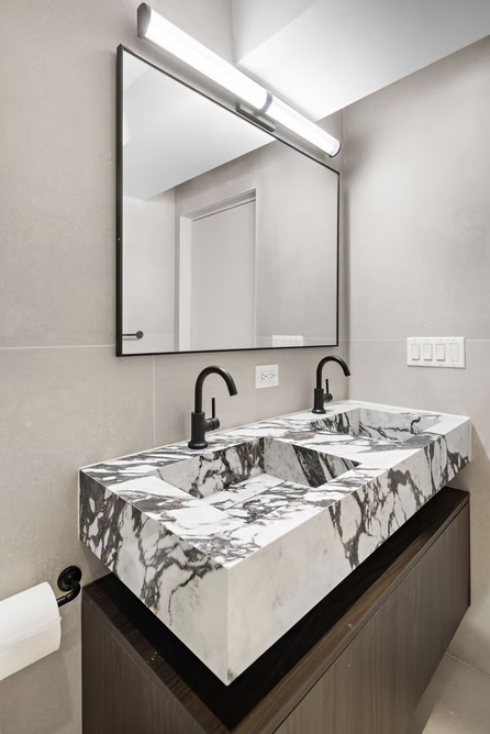 Twin marble basins with black fittings and framed mirror