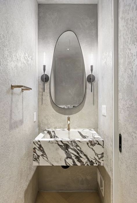 Cloakroom in micro cement with sculptural marble basin and oval mirror