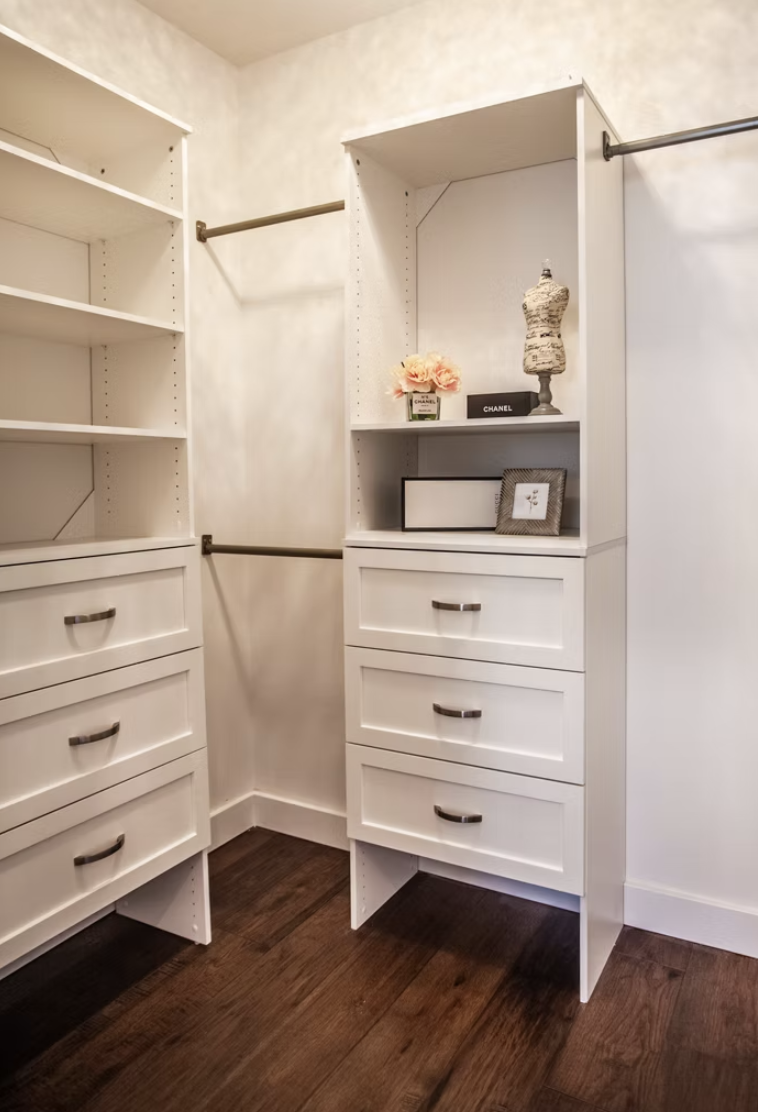 Fitted walk in wardrobe with white joinery and dark timber flooring