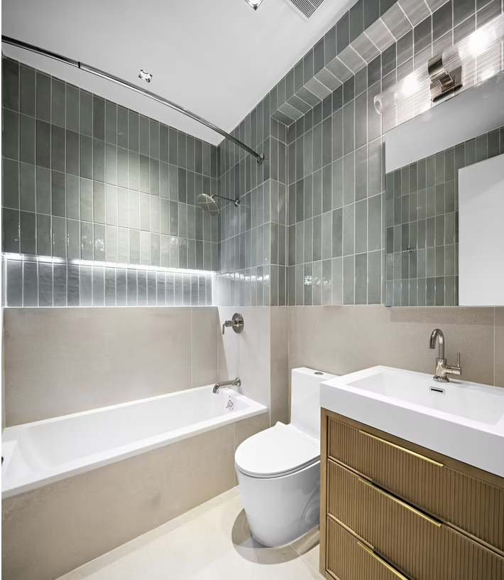 Bathroom with bath, green tiled surround and brass ribbed vanity